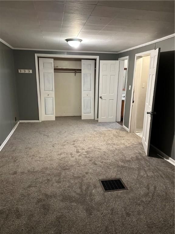 unfurnished bedroom featuring carpet, a closet, and crown molding