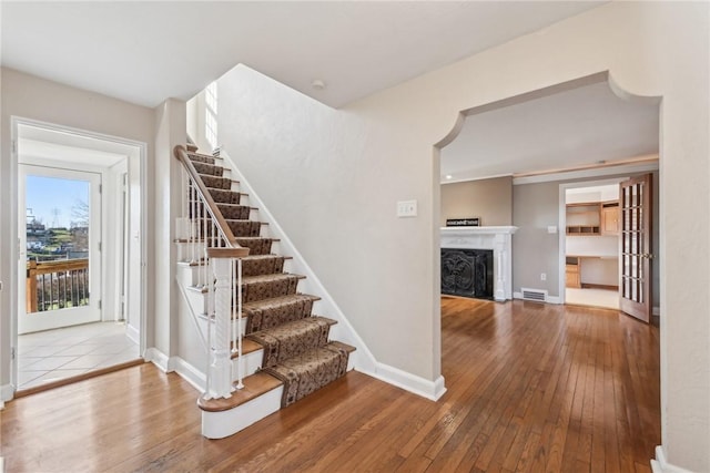 stairway with hardwood / wood-style floors and french doors