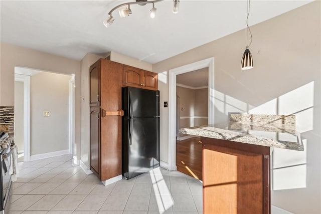 kitchen with black refrigerator, light stone countertops, ornamental molding, decorative light fixtures, and light tile patterned flooring