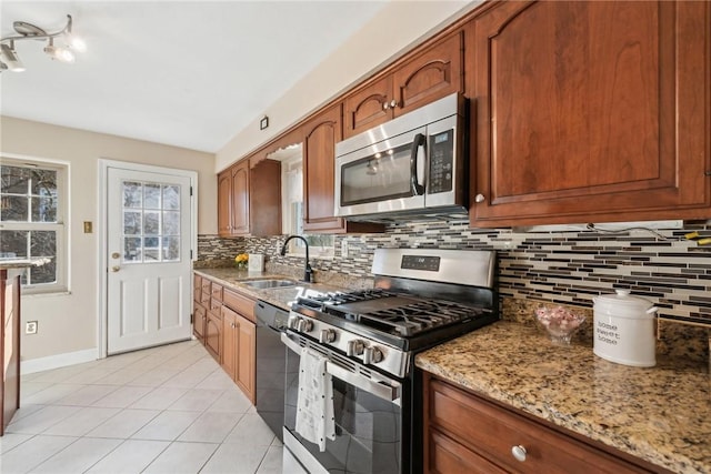 kitchen featuring sink, light stone counters, decorative backsplash, light tile patterned floors, and appliances with stainless steel finishes