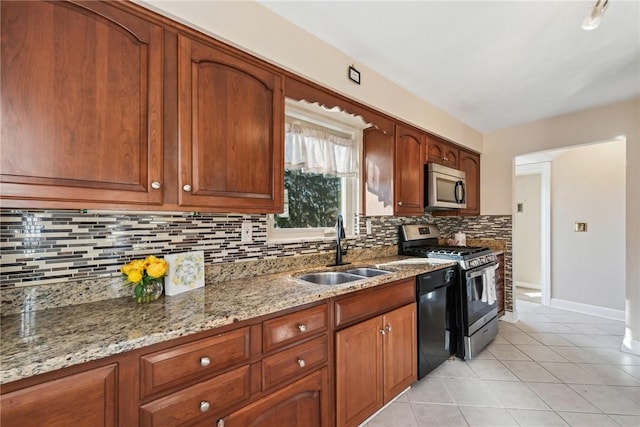 kitchen featuring light stone countertops, sink, decorative backsplash, light tile patterned flooring, and appliances with stainless steel finishes