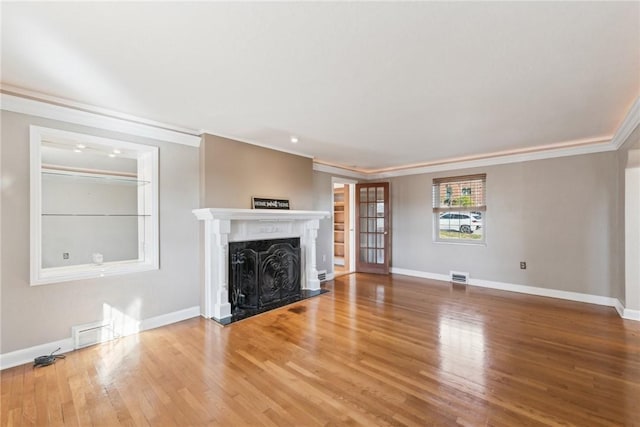 unfurnished living room featuring a high end fireplace, hardwood / wood-style flooring, and crown molding