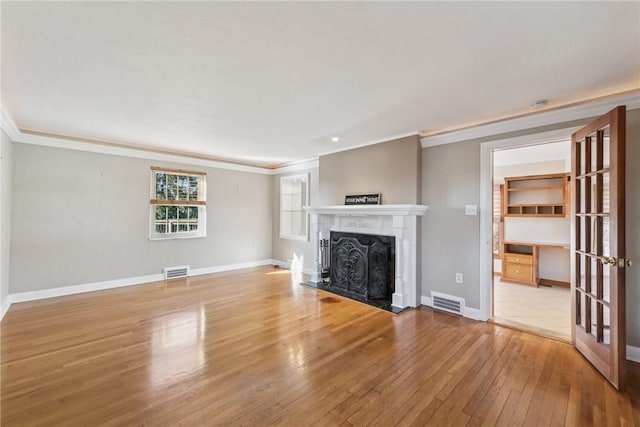 unfurnished living room featuring light hardwood / wood-style floors, ornamental molding, and a high end fireplace