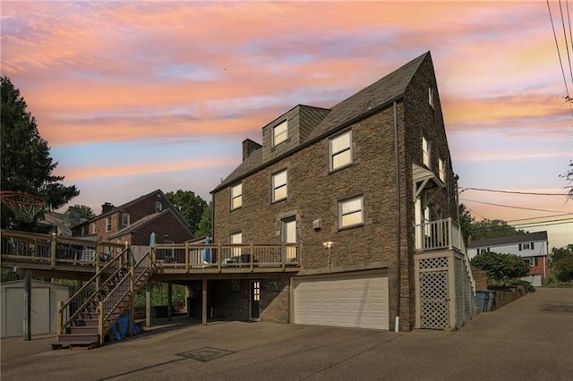 back house at dusk with a garage and a deck