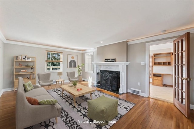 living room with hardwood / wood-style floors, a premium fireplace, and ornamental molding