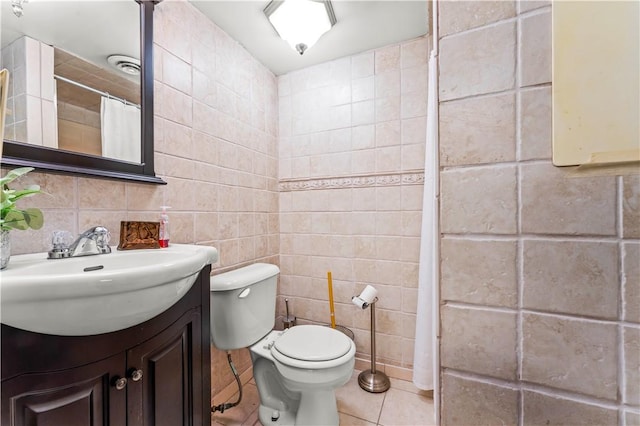 bathroom featuring toilet, vanity, tile patterned floors, and tile walls