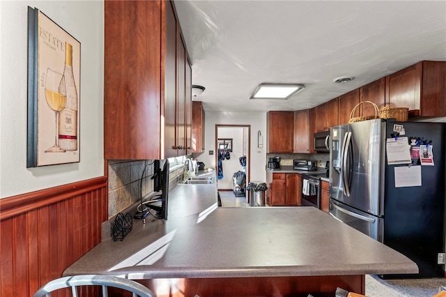 kitchen featuring kitchen peninsula, backsplash, stainless steel appliances, and sink