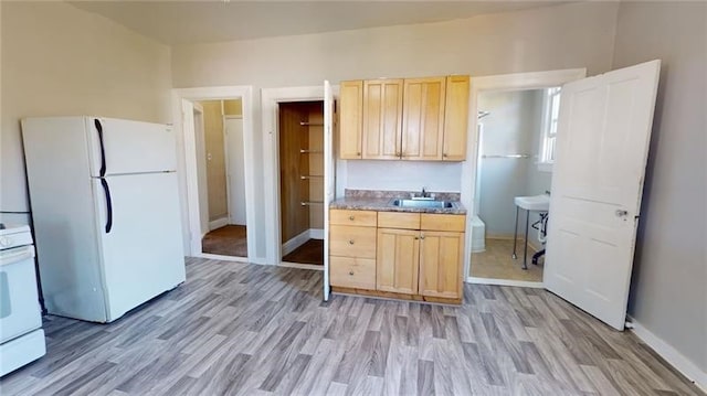 kitchen with light brown cabinets, white appliances, light hardwood / wood-style flooring, and sink