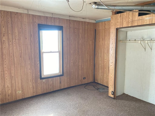 unfurnished bedroom with wood walls and carpet floors