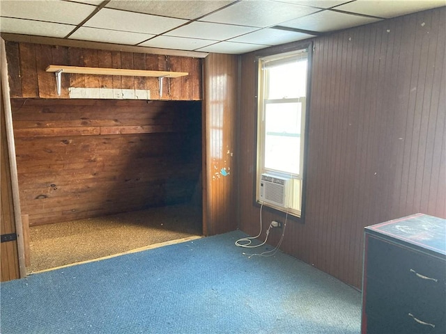 empty room featuring a paneled ceiling, cooling unit, and wood walls