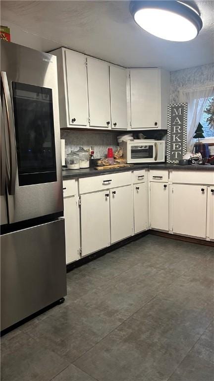 kitchen with white cabinets, backsplash, and stainless steel refrigerator