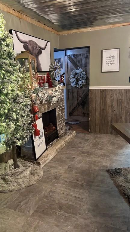 interior space with a stone fireplace, wooden ceiling, and wooden walls