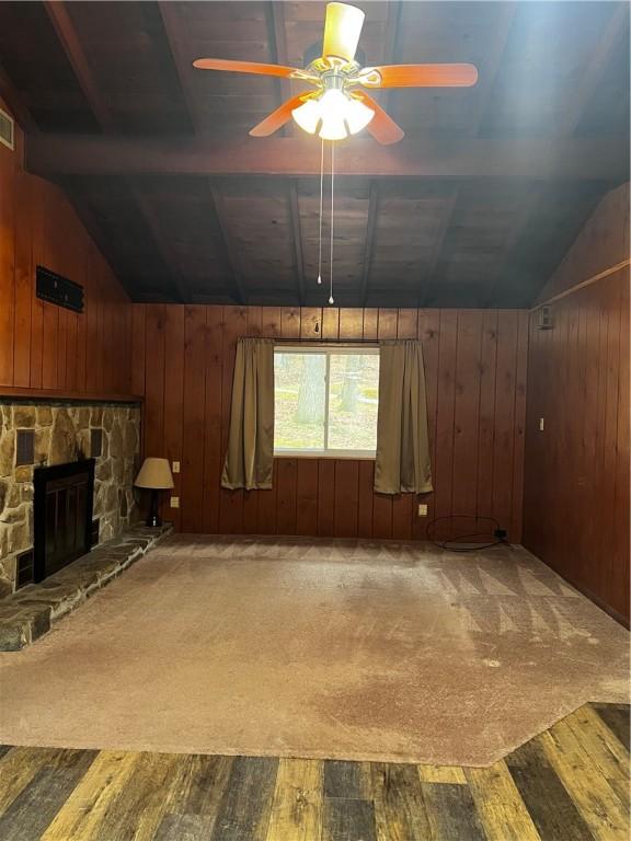 unfurnished living room featuring wood walls, hardwood / wood-style floors, ceiling fan, and lofted ceiling