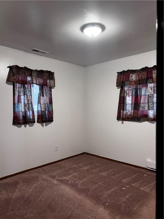 empty room with carpet floors and a baseboard radiator