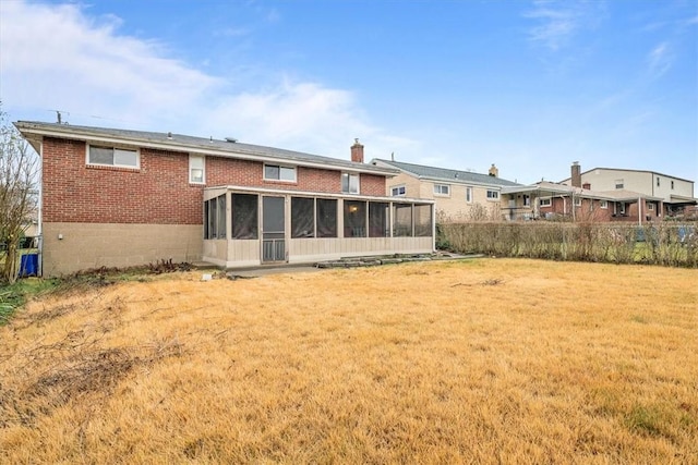 back of property with a sunroom and a yard