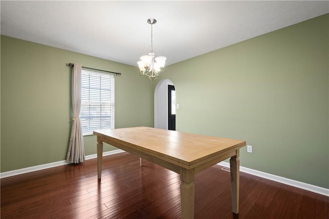 unfurnished dining area with dark wood-type flooring and a notable chandelier