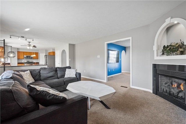 carpeted living room with ceiling fan and a tiled fireplace