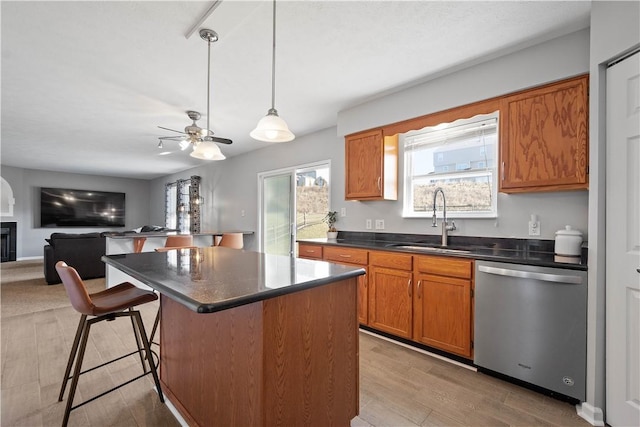 kitchen featuring dishwasher, a center island, a breakfast bar, sink, and light wood-type flooring