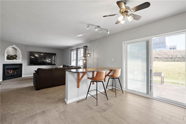 kitchen with kitchen peninsula, a kitchen breakfast bar, light carpet, and ceiling fan