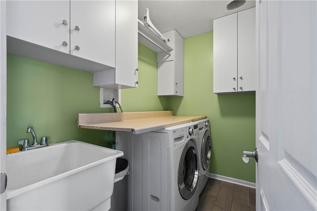 laundry area featuring cabinets, dark hardwood / wood-style floors, washing machine and clothes dryer, and sink