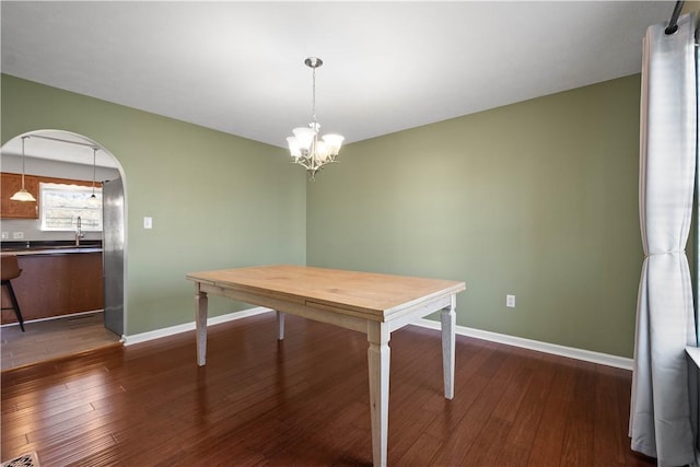 unfurnished dining area with dark hardwood / wood-style floors, an inviting chandelier, and sink