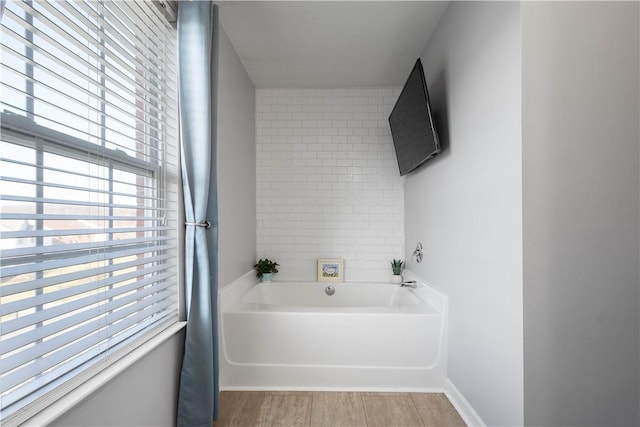 bathroom featuring hardwood / wood-style floors and a tub to relax in