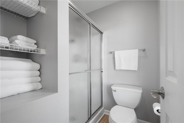 bathroom featuring hardwood / wood-style flooring, toilet, and a shower with shower door