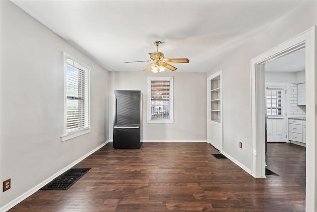 interior space with built in shelves, ceiling fan, and dark wood-type flooring