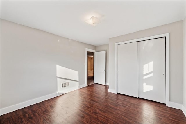 unfurnished bedroom with a closet and dark hardwood / wood-style floors