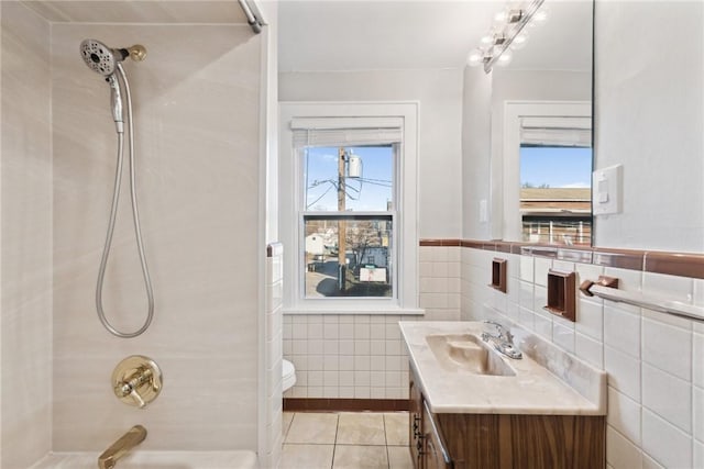 full bathroom with tile patterned floors,  shower combination, toilet, vanity, and tile walls