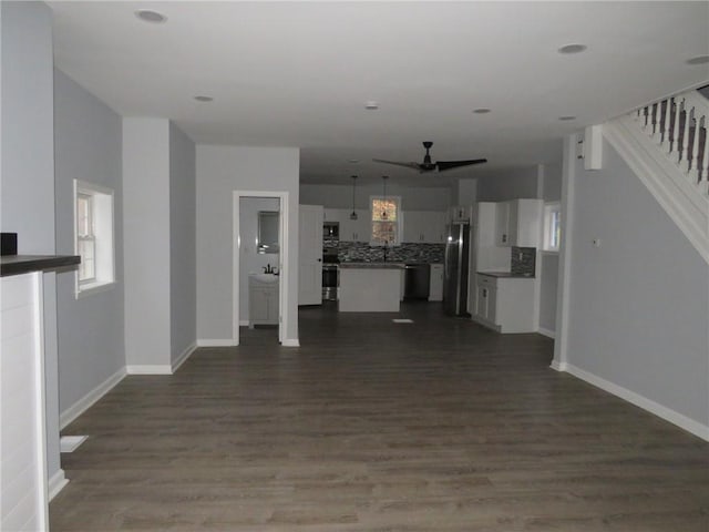 unfurnished living room featuring dark hardwood / wood-style floors, ceiling fan, and sink