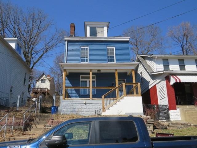 american foursquare style home with stairs, a porch, and a chimney