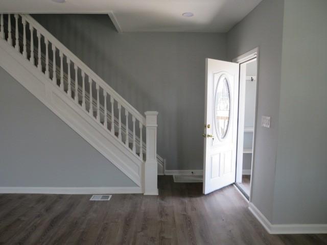 foyer featuring stairway, visible vents, baseboards, and wood finished floors