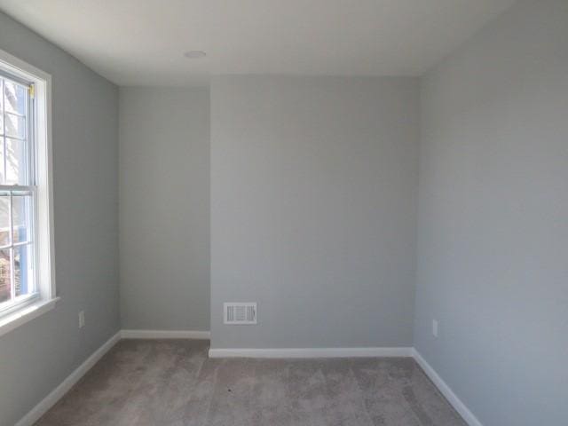 unfurnished room with visible vents, light carpet, and baseboards