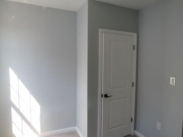 spare room with baseboards and light carpet