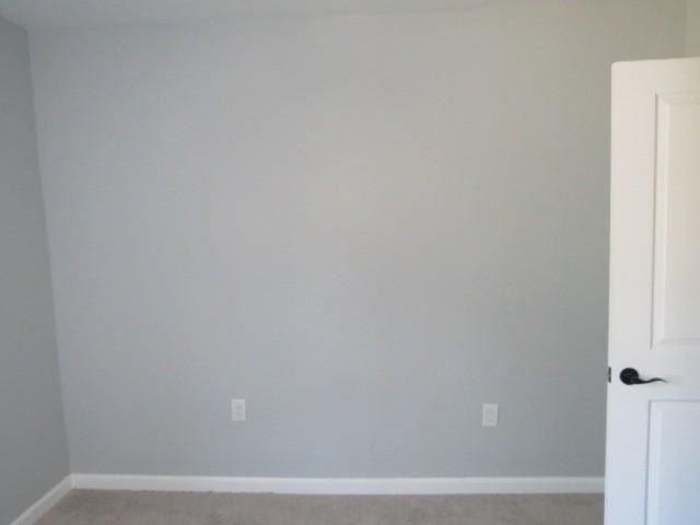 unfurnished room featuring light colored carpet and baseboards