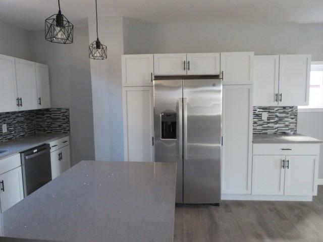 kitchen featuring white cabinetry, stainless steel fridge with ice dispenser, pendant lighting, dishwasher, and light wood-type flooring