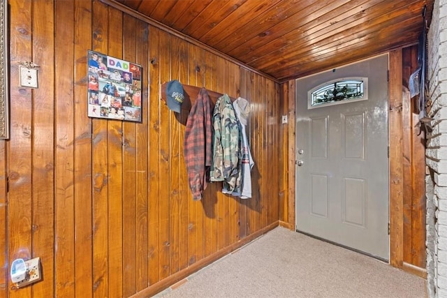 entryway with wood ceiling, light carpet, and wooden walls