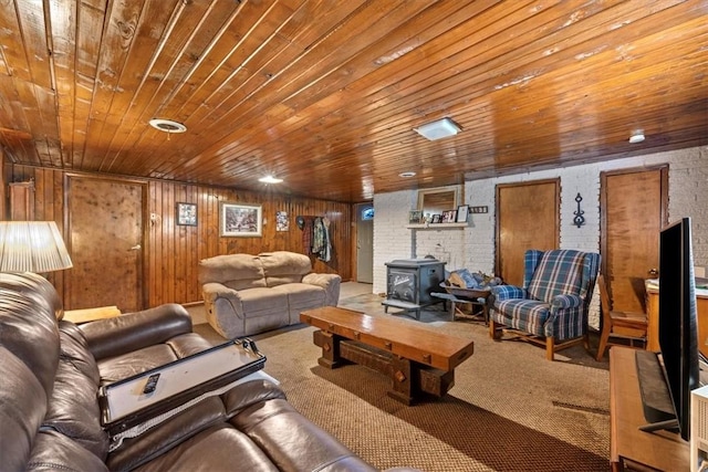 living room featuring carpet flooring, a wood stove, wood walls, and wooden ceiling