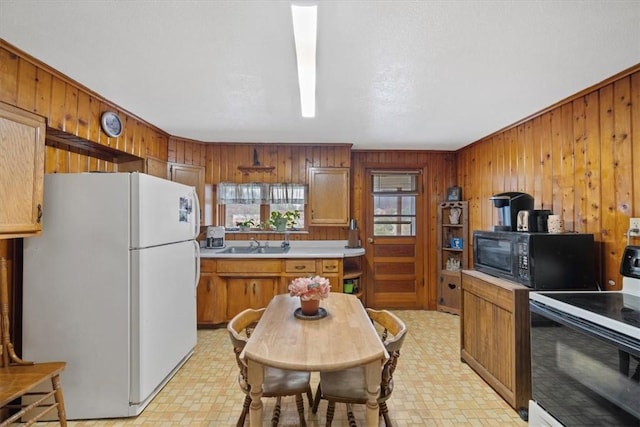 kitchen with wooden walls, crown molding, black appliances, and sink