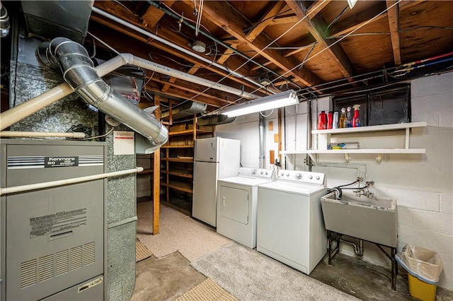 basement featuring washer and clothes dryer, sink, and white refrigerator