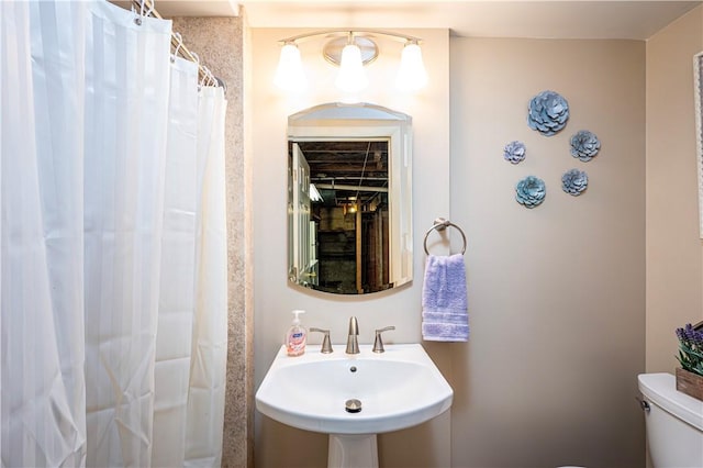 bathroom featuring a shower with curtain, toilet, and sink