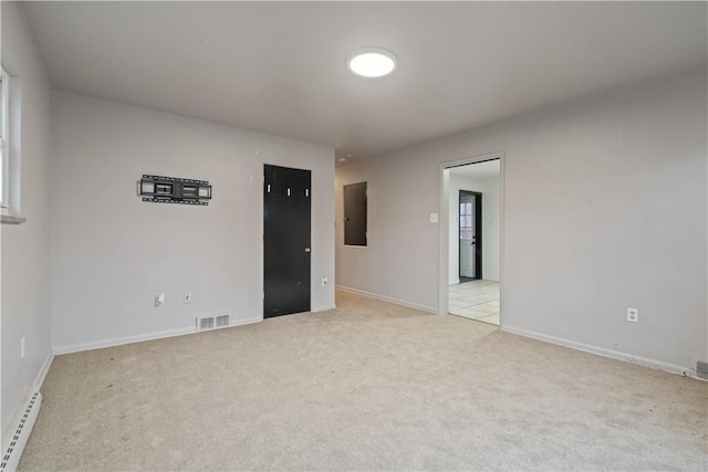 carpeted spare room featuring baseboard heating and electric panel