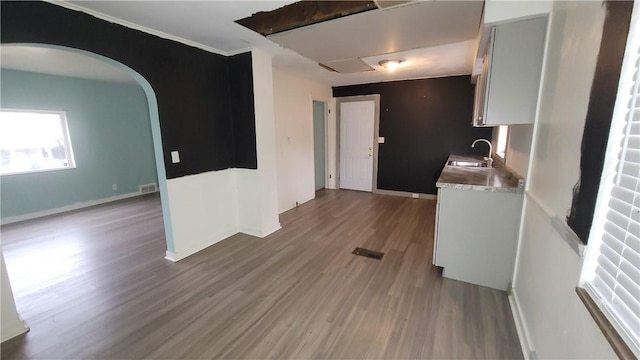 kitchen featuring hardwood / wood-style flooring, white cabinetry, crown molding, and sink