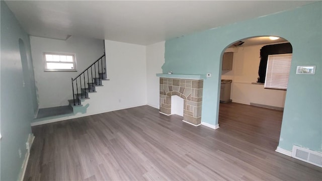 unfurnished living room featuring hardwood / wood-style flooring and a stone fireplace