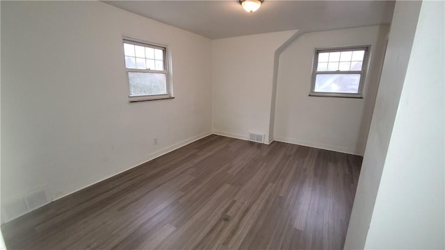 empty room featuring a healthy amount of sunlight and dark hardwood / wood-style floors