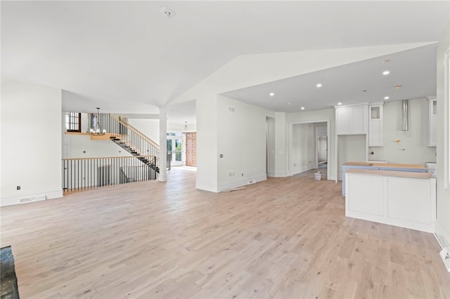 unfurnished living room with light hardwood / wood-style floors and vaulted ceiling