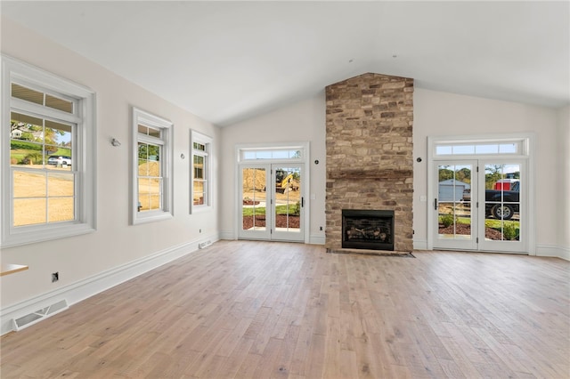 unfurnished living room featuring a stone fireplace, french doors, light hardwood / wood-style floors, and lofted ceiling