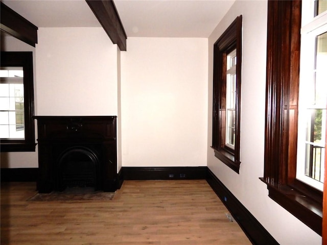 living room with beam ceiling, a healthy amount of sunlight, and wood-type flooring