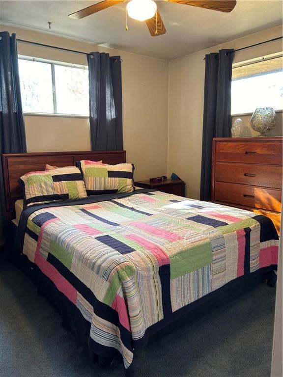 carpeted bedroom featuring multiple windows and ceiling fan